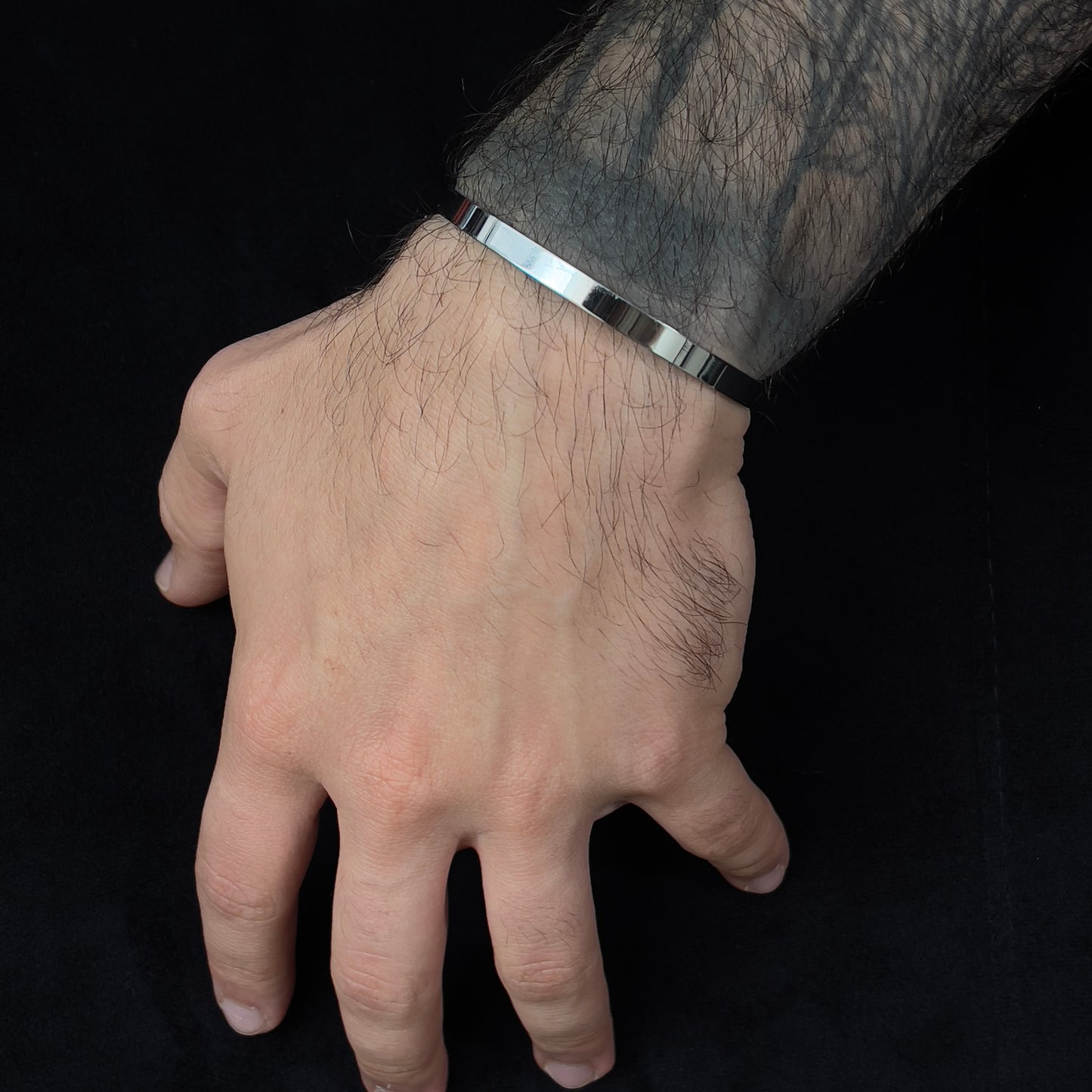 Detalhe da pulseira prateada ajustável em forma de C, com brilho metálico e acabamento premium da The Iron Essence