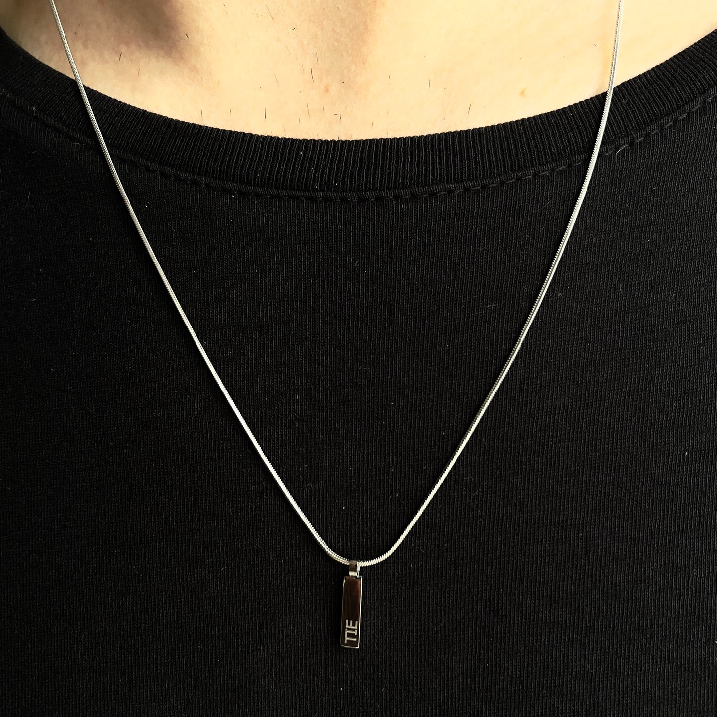 Detalhe do pendente quadrado prateado em aço inoxidável 316L de colar clássico da The Iron Essence